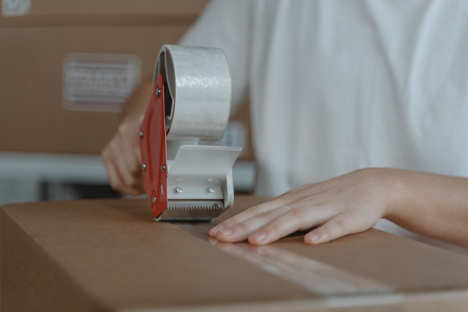 Hands applying clear tape to close a shipping carton